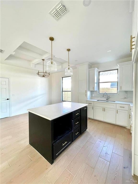 kitchen featuring white cabinetry, a center island, hanging light fixtures, and light hardwood / wood-style flooring