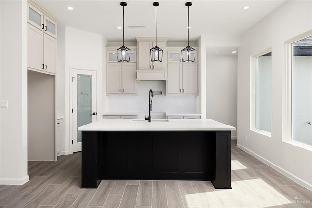 904 N Trinity St, Edinburg, TX 78541 - kitchen with light wood finished floors, light countertops, a center island with sink, glass insert cabinets, and pendant lighting