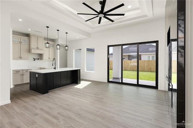 904 N Trinity St, Edinburg, TX 78541 - kitchen with a raised ceiling, light countertops, a kitchen island with sink, ceiling fan, and light wood-style floors