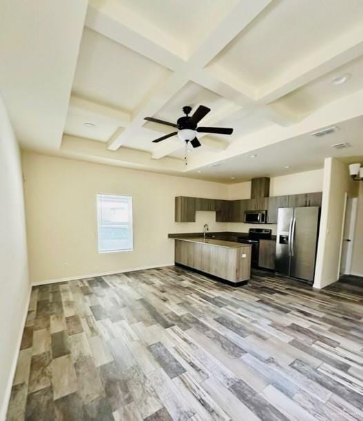 kitchen featuring beam ceiling, light wood-type flooring, stainless steel appliances, and coffered ceiling