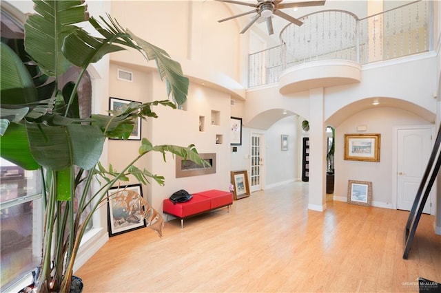 interior space featuring wood finished floors, visible vents, baseboards, arched walkways, and a towering ceiling