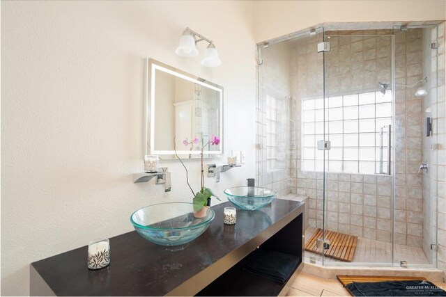 full bathroom featuring double vanity, a stall shower, and a sink