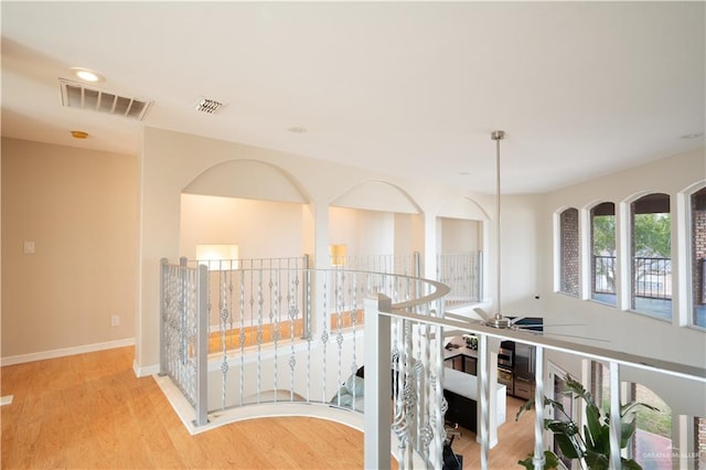 hall with wood finished floors, visible vents, and baseboards