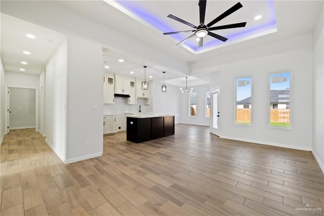 700 Juan Seguin St, Weslaco, TX 78599 - unfurnished living room featuring a ceiling fan, a raised ceiling, light wood-style flooring, a sink, and baseboards