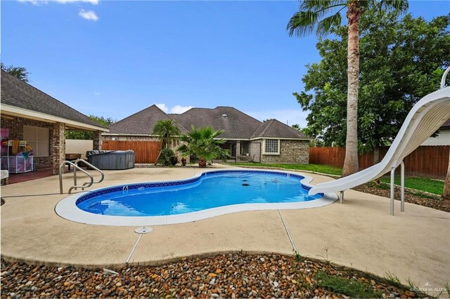 view of pool featuring a water slide, a patio, and a hot tub