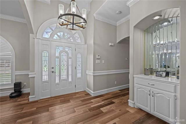 foyer with crown molding, hardwood / wood-style floors, and an inviting chandelier