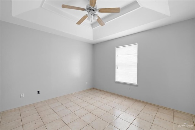 spare room with light tile patterned floors, a tray ceiling, and ceiling fan