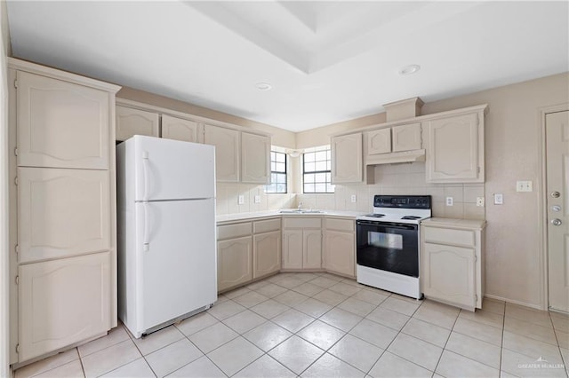 kitchen with sink, light tile patterned floors, range with electric cooktop, white refrigerator, and decorative backsplash