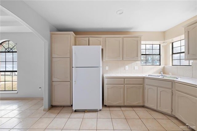 kitchen featuring white refrigerator, light tile patterned flooring, sink, and decorative backsplash