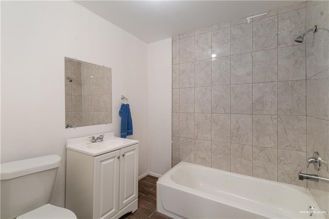 full bathroom featuring hardwood / wood-style flooring, tiled shower / bath, vanity, and toilet