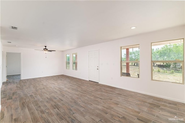 unfurnished room featuring ceiling fan, a healthy amount of sunlight, and dark hardwood / wood-style flooring