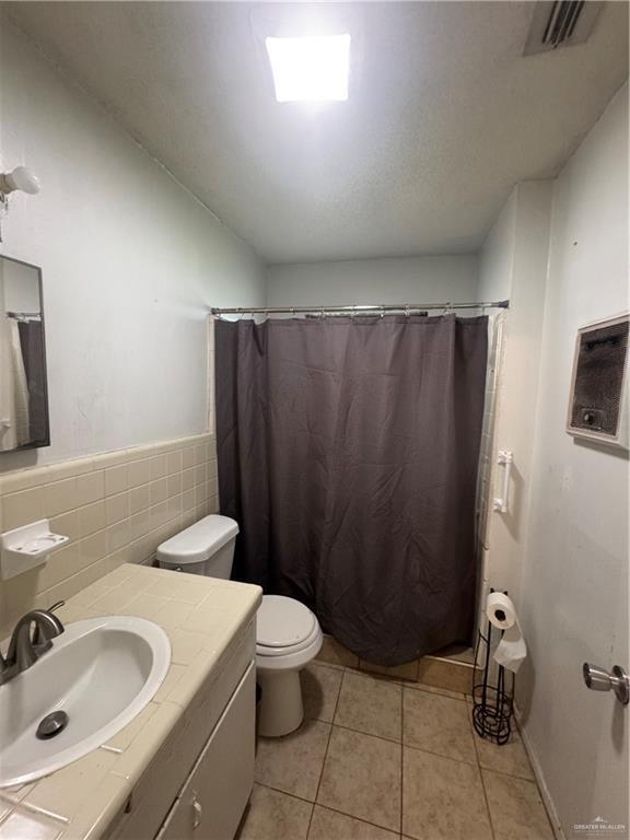 1008 S 3rd St, Edinburg, TX 78539 - full bathroom featuring vanity, tile patterned flooring, curtained shower, and tile walls