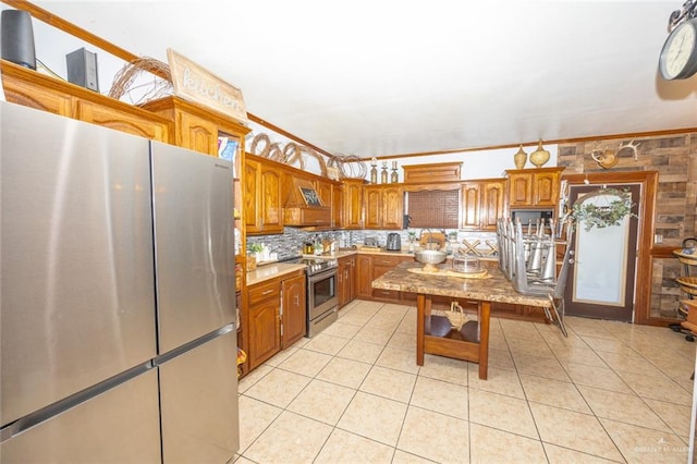 kitchen featuring light tile patterned floors, backsplash, appliances with stainless steel finishes, a kitchen island, and ornamental molding