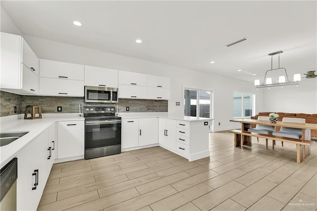 2208 Providence Ave, Mcallen, TX 78504 - kitchen featuring stainless steel appliances, a peninsula, backsplash, light countertops, and white cabinetry