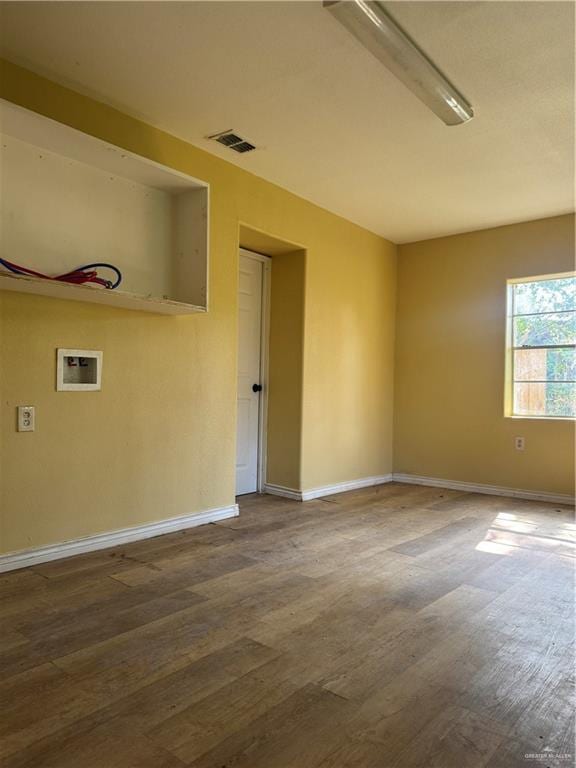 spare room with baseboards, wood finished floors, and visible vents