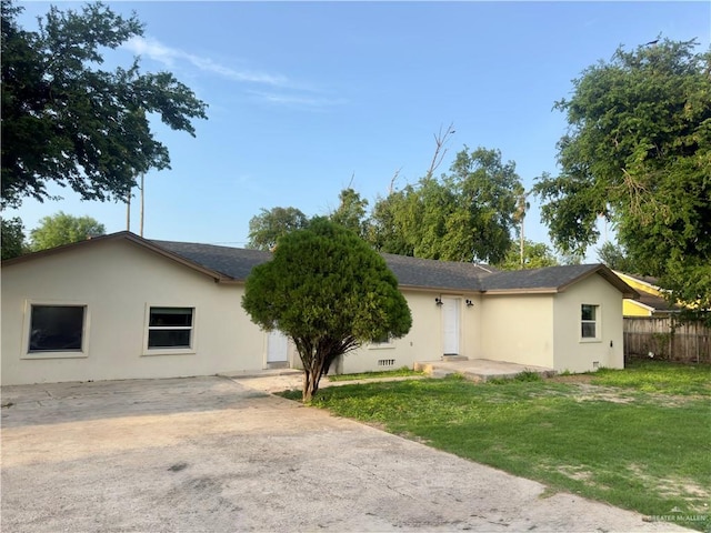view of front of property featuring fence, a front yard, and stucco siding