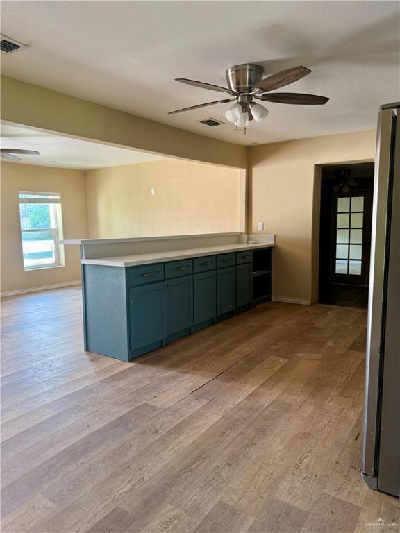 kitchen with freestanding refrigerator, a ceiling fan, visible vents, and light wood-style floors