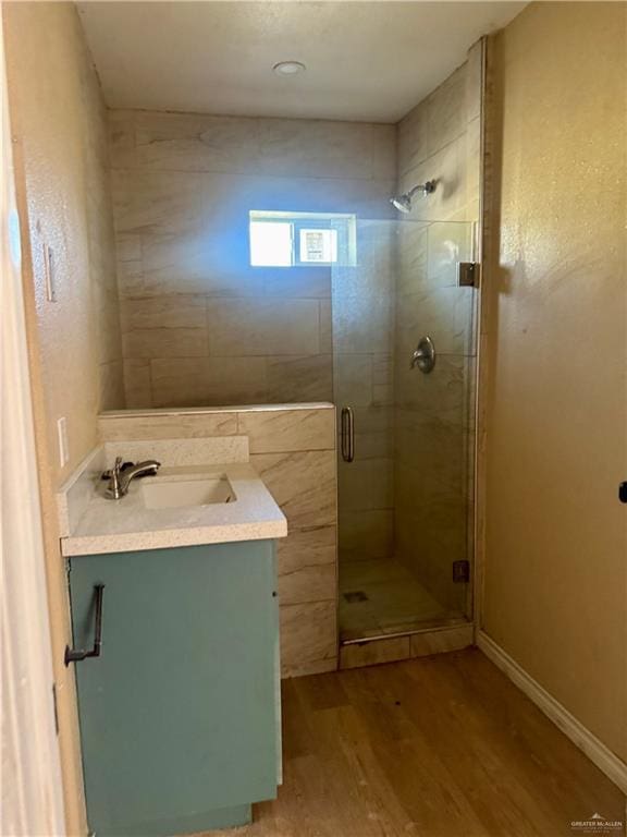 full bathroom featuring vanity, baseboards, a stall shower, and wood finished floors
