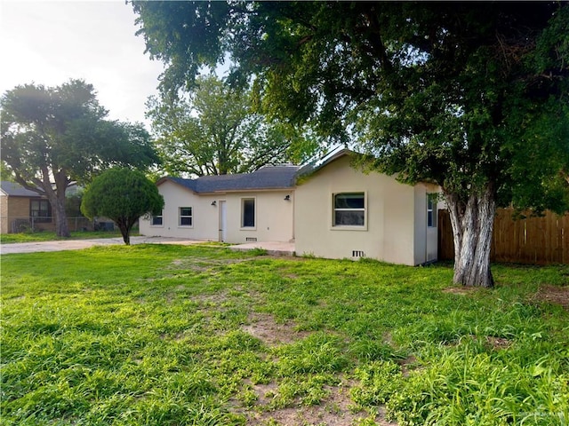 back of house with fence, stucco siding, and a yard