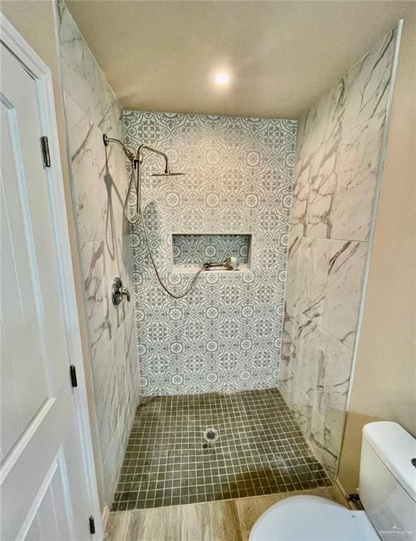 bathroom with a tile shower and toilet