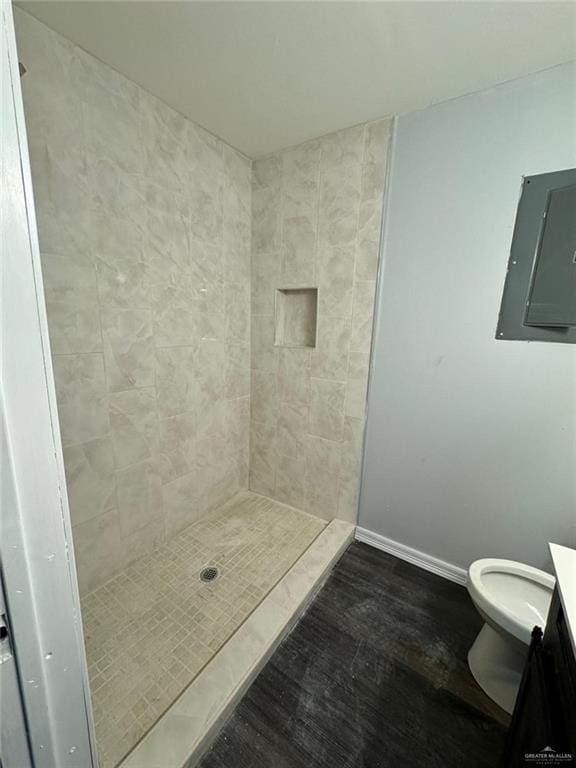 bathroom featuring tiled shower, vanity, electric panel, and toilet