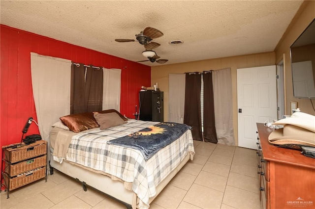408 E Ebony St, La Feria, TX 78559 - bedroom with light tile patterned flooring, a textured ceiling, a ceiling fan, and wooden walls
