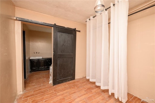 408 E Ebony St, La Feria, TX 78559 - corridor with a barn door, wood finished floors, and a textured ceiling