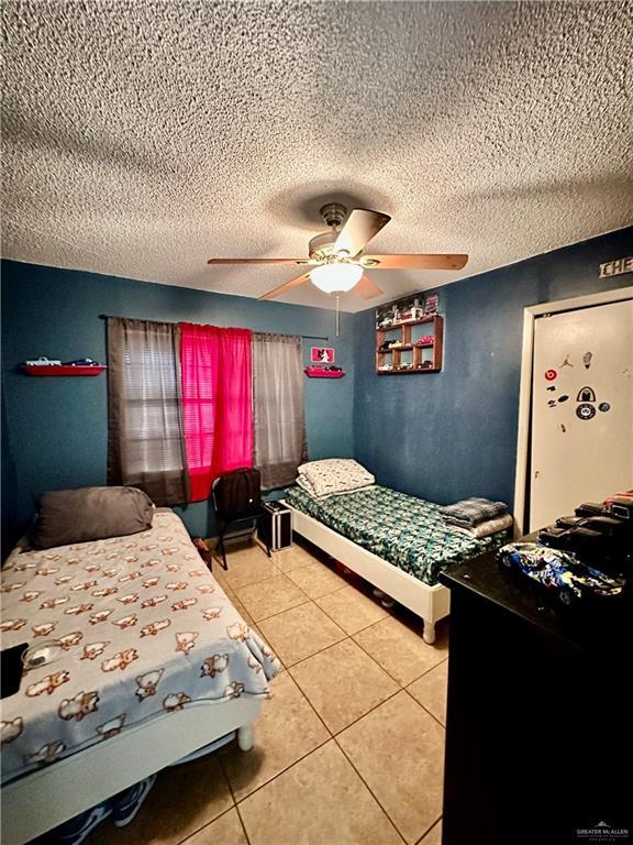 bedroom with light tile patterned floors, a ceiling fan, and a textured ceiling