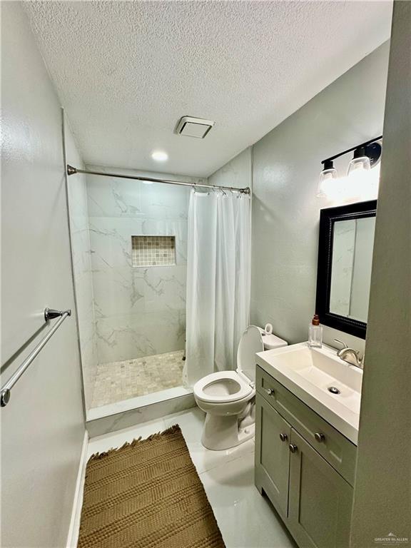 bathroom with vanity, visible vents, a stall shower, a textured ceiling, and toilet