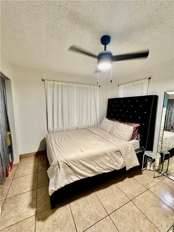 tiled bedroom featuring a textured ceiling and a ceiling fan