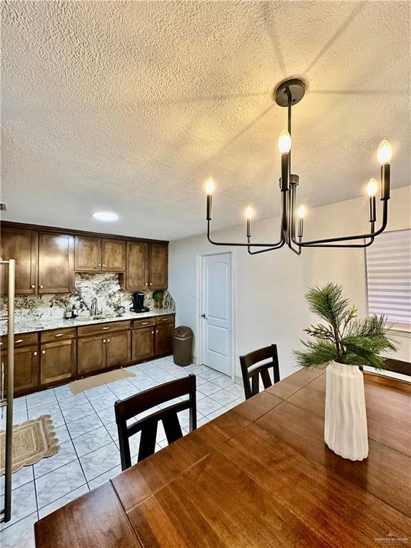 unfurnished dining area with light tile patterned floors, a textured ceiling, and a sink