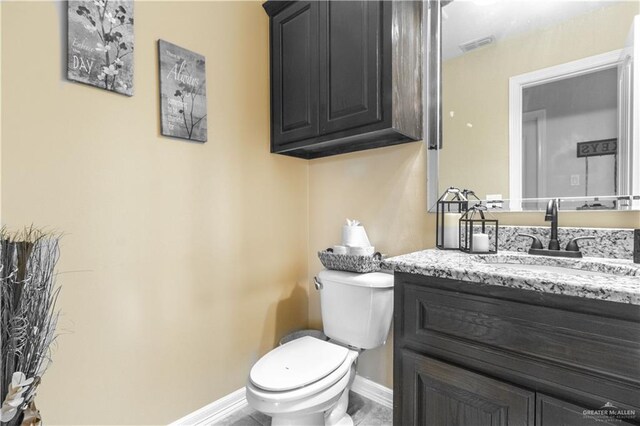 half bathroom featuring baseboards, visible vents, toilet, and vanity