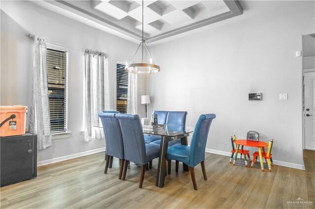 dining room with a notable chandelier, coffered ceiling, baseboards, and wood finished floors