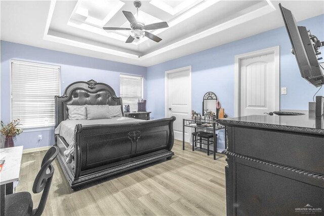 bedroom featuring a tray ceiling, light wood-type flooring, and ceiling fan