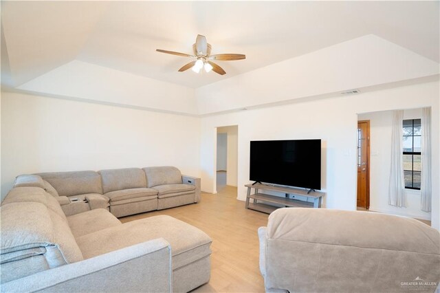 living room with light hardwood / wood-style floors, ceiling fan, and a tray ceiling