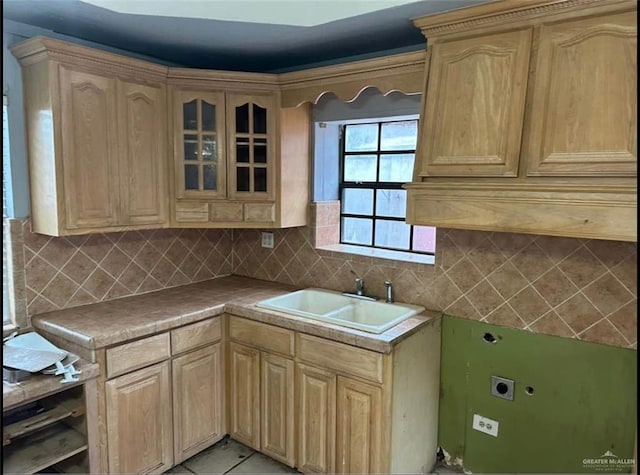 kitchen with light tile patterned floors, tasteful backsplash, light brown cabinetry, and sink