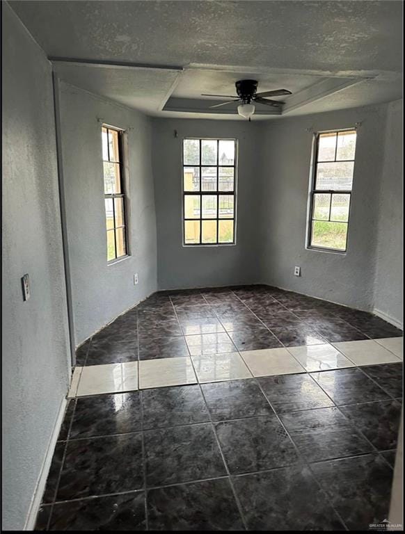 unfurnished room featuring plenty of natural light, ceiling fan, and a tray ceiling