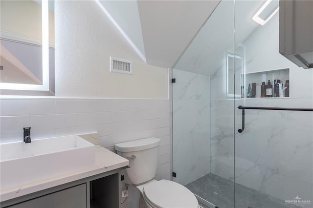 bathroom featuring toilet, vanity, a marble finish shower, lofted ceiling, and visible vents