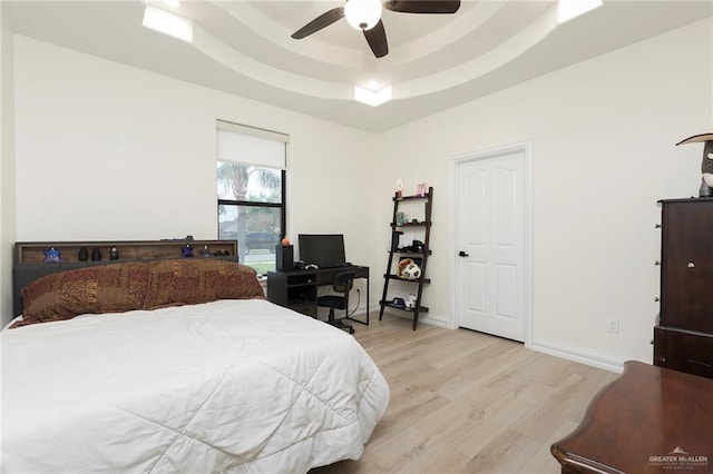 bedroom with a raised ceiling, baseboards, light wood-style floors, and ceiling fan