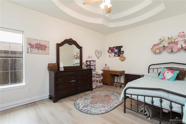 bedroom with baseboards, wood finished floors, a ceiling fan, and a raised ceiling