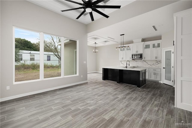 4911 Aguajito St, Edinburg, TX 78542 - kitchen with hardwood / wood-style floors, pendant lighting, a kitchen island with sink, white cabinets, and ceiling fan with notable chandelier