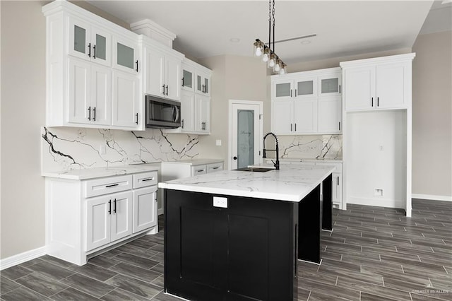 4911 Aguajito St, Edinburg, TX 78542 - kitchen with tasteful backsplash, light stone counters, a kitchen island with sink, sink, and white cabinets