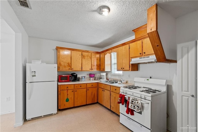 kitchen with sink, white appliances, and a textured ceiling