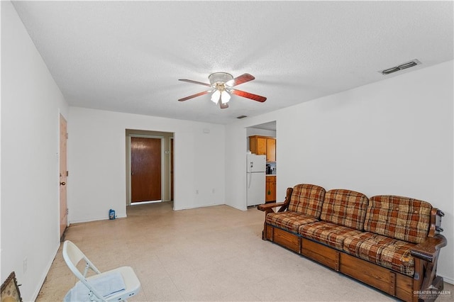 living room featuring ceiling fan and a textured ceiling