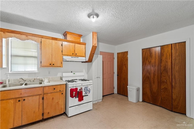 kitchen featuring a textured ceiling, white range with gas stovetop, and sink