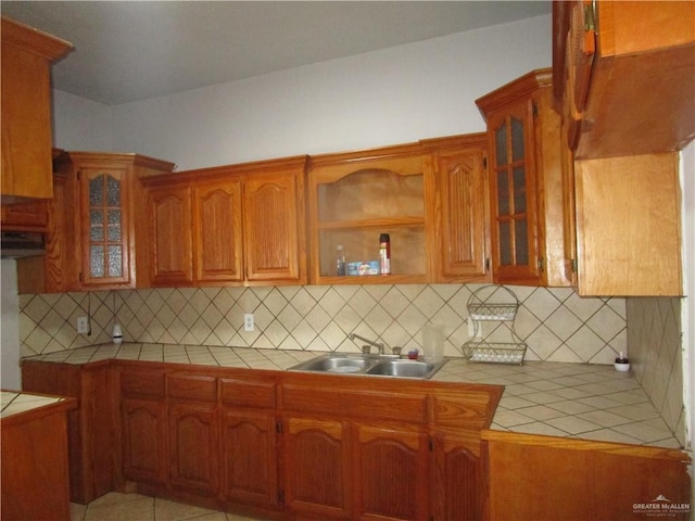 5401 Sunny Cir, Mission, TX 78574 - kitchen with tile countertops, ventilation hood, brown cabinets, backsplash, and glass insert cabinets