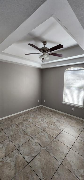 tiled empty room featuring ceiling fan and a textured ceiling