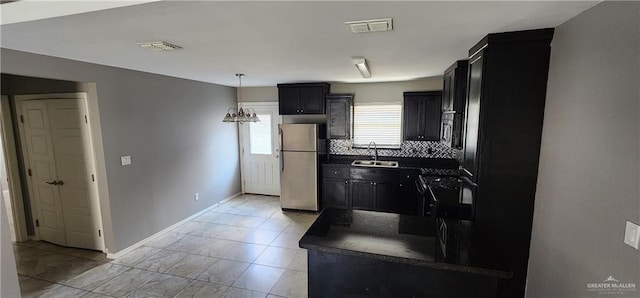 kitchen with sink, a notable chandelier, pendant lighting, decorative backsplash, and appliances with stainless steel finishes