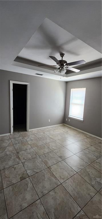 spare room featuring a raised ceiling and ceiling fan