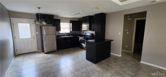 kitchen featuring appliances with stainless steel finishes, backsplash, sink, an inviting chandelier, and a center island